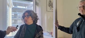 Una residente mostra alla stampa com'è cambiato il panorama dalla sua casa: adesso il grande hotel le toglie luce, un domani le toglierà pure la privacy