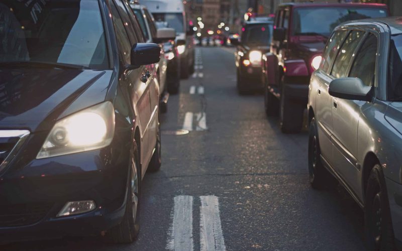Two rows of cars with headlights on, on a city road. Original public domain image from Wikimedia Commons